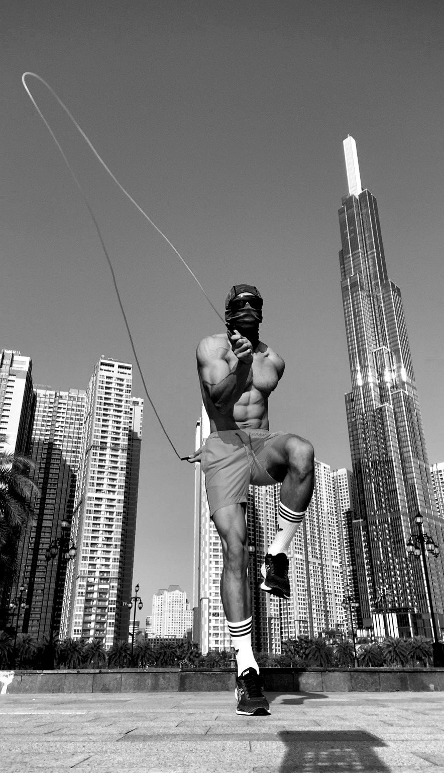 Masked athlete jumping rope before a tall city skyline.